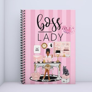 May include: Pink and black spiral bound notebook with the text "boss lady" in black script. The cover features a cartoon illustration of a woman sitting at a desk with a laptop, a cat, and office supplies. The text "mave designs" is in a pink and white font.