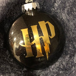 May include: Black Christmas ornament with gold glitter and a gold "HP" logo with a lightning bolt.