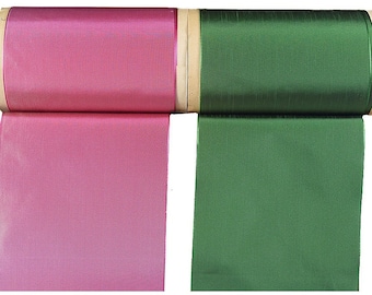 May include: Two spools of ribbon, one pink and one green, are unfurled and ready to be used for crafting or decorating.