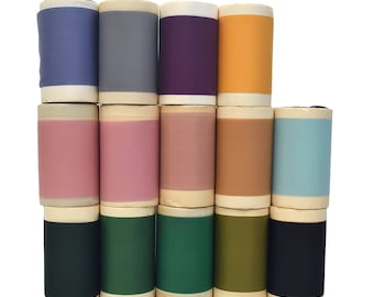 May include: A collection of spools of thread in various colors, including purple, orange, pink, green, blue, and brown. The spools are arranged in a staggered pattern, with the top row having seven spools and the bottom row having eight spools.