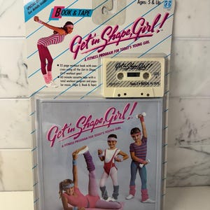 May include: A Get in Shape, Girl! fitness program set in original packaging, featuring a 60-minute cassette tape and a 32-page workout book. The packaging displays illustrations of children in 1980s-style workout gear, including leotards, leggings, and leg warmers, with the text Get in Shape, Girl! A Fitness Program for Today's Young Girl.