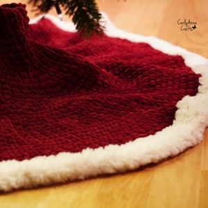 May include: A red knitted Christmas tree skirt with a white faux fur trim. The skirt is made with a chunky yarn and has a textured, puffy look.