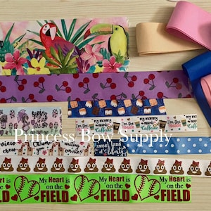 May include: A collection of decorative ribbons in various patterns and colors. Designs include tropical birds, cherries, coffee cups, giraffes, and baseballs with the text "My Heart is on the FIELD". Also, solid ribbons in pink, blue, and tan.