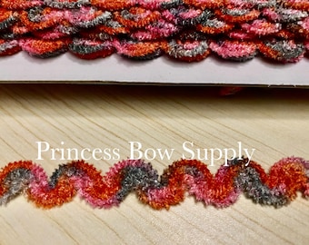Può includere: Primo piano di un bordo decorativo con un design ondulato. Il bordo presenta una combinazione di colori arancione, rosa e grigio. Il testo "Princess Bow Supply" è visibile nell'immagine.