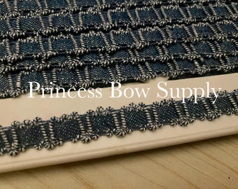 Può includere: Primo piano di un rotolo di passamaneria decorativa blu navy e bianca. La passamaneria presenta un motivo quadrato ripetuto con un bordo smerlato. Il testo "Princess Bow Supply" è visibile.