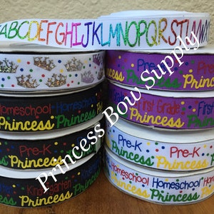 Pu&ograve; includere: Una pila di rotoli di nastro con vari disegni. Un rotolo presenta l'alfabeto in glitter arcobaleno, mentre altri mostrano corone, le parole "Homeschool Princess", "Pre-K Princess" e "First Grade Princess". I nastri sono di vari colori.