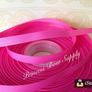 May include: A spool of bright pink ribbon. The ribbon is tightly wound and has a slightly textured surface. The text "Princess Bow Supply" is visible on the image. The ribbon is likely used for crafting or gift wrapping.