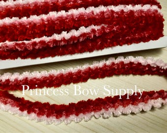 Può includere: Primo piano di nastro soffice rosso e bianco. Il nastro è di un rosso vibrante con bordi bianchi, creando un bordo decorativo strutturato. Il testo "Princess Bow Supply" è visibile sul nastro.