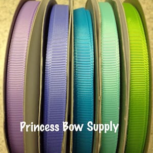 May include: Spools of colorful grosgrain ribbon in shades of purple, blue, teal, and green. The ribbon is neatly wound on cardboard spools. The text "Princess Bow Supply" is printed on the bottom of the image.