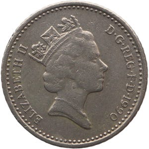 Może przedstawiać: Srebrna moneta z profilem ukoronowanej głowy, z napisami "ELIZABETH II" i "D.G.REG.F.D.1990". Moneta ma szczegółowy wzór i teksturowaną powierzchnię.