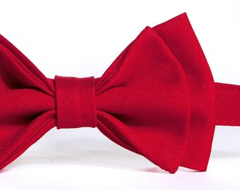 May include: A red bow tie made of fabric. The bow tie is tied and ready to wear.