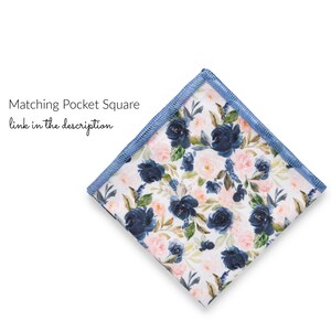 K&ouml;nnte beinhalten: Ein wei&szlig;es Einstecktuch mit einem blauen Blumenmuster. Das Einstecktuch hat einen blauen Rand.