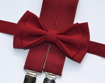 May include: A set of burgundy suspenders with matching bow tie. The suspenders have silver clips and the bow tie is made of a textured fabric.