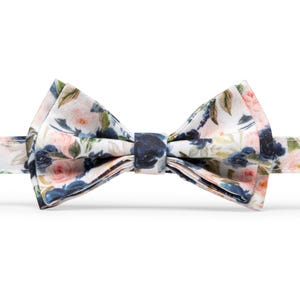 K&ouml;nnte beinhalten: Ein wei&szlig;er Fliege mit einem Blumenmuster mit rosa und blauen Blumen.