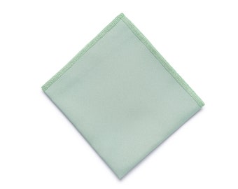 Può includere: Un tovagliolo di stoffa quadrato di colore verde chiaro con un bordo cucito di colore verde chiaro.