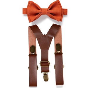 May include: A set of brown leather suspenders with gold-tone clips and a burnt orange bow tie.
