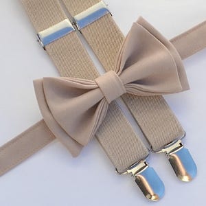 May include: A beige bow tie and suspenders set. The bow tie is made of a soft, smooth fabric and has a classic shape. The suspenders are adjustable and have silver clips.
