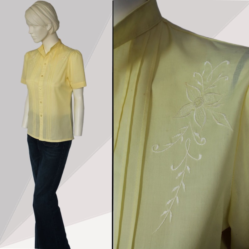 Puede incluir: Una camisa de botones de color amarillo p&aacute;lido con mangas cortas y un dise&ntilde;o floral bordado en blanco en el hombro derecho.