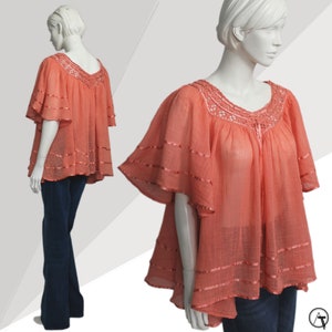 May include: A coral pink, sheer, lightweight blouse with a lace trim neckline and ruffled sleeves. The blouse has a high-low hemline and is made of a soft, flowing fabric.