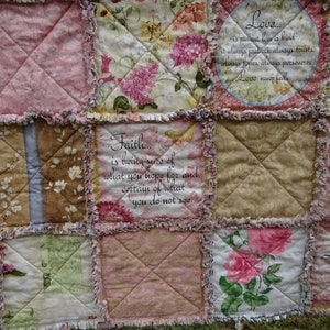 May include: A patchwork quilt with various floral patterns and inspirational quotes. The quilt features squares of pink, beige, and green fabric, some with printed roses and other flowers. The text includes phrases like "Love never fails" and "Let Your Light Shine Bright."