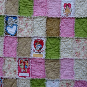 May include: A patchwork quilt with a variety of floral and heart-themed fabric squares. The quilt is made with a mix of pink, green, brown, and white fabrics. The quilt is quilted with a simple diamond pattern.