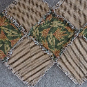 K&ouml;nnte beinhalten: Ein brauner und gr&uuml;ner Patchwork-Tischl&auml;ufer mit einem Weizenmuster. Der L&auml;ufer besteht aus Stoffquadraten, die mit einem braunen Netzstoff zusammengen&auml;ht sind.