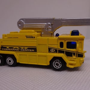 May include: Yellow Tonka LAX Command Center toy fire truck with a silver extending ladder. The toy truck has black accents and the number 14 on the side. The toy has black wheels and blue lights.