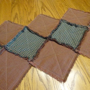 May include: A patchwork table runner made of red and green plaid fabric with frayed edges.