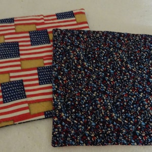 May include: Two quilted pot holders. One is red, white, and blue with a pattern of American flags. The other is navy blue with red, white, and blue speckles.