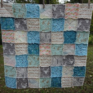 May include: A patchwork quilt with a variety of fabrics in shades of blue, gray, and white. The quilt features a deer print, arrow print, and geometric patterns.