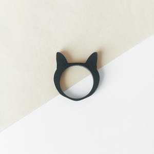 Op de afbeelding: Zwarte ring in de vorm van een kat met een gladde, matte afwerking.