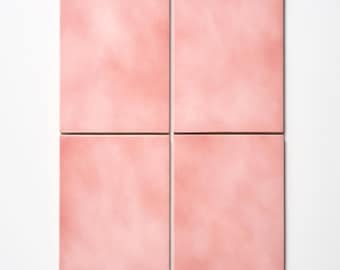 May include: Four square, blush-pink tiles arranged in a grid pattern. The tiles have a slightly textured appearance and a soft, matte finish. The tiles are a solid color, with subtle variations in tone, and are set against a white background.