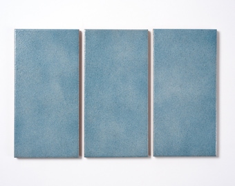 May include: Three rectangular ceramic tiles in a light blue color. The tiles have a subtle, uneven texture.