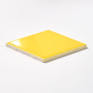 May include: A single yellow ceramic tile with a glossy finish.