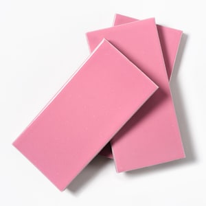 May include: Three pink ceramic tiles stacked on top of each other.
