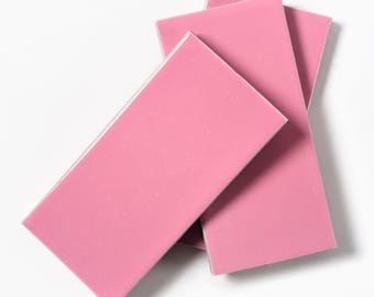 May include: Three pink ceramic tiles stacked on top of each other.