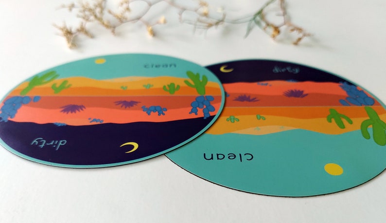 Pu&ograve; includere: Due sottobicchieri rotondi, colorati e illustrati con una scena del deserto. Un sottobicchiere dice "pulito" e l'altro dice "sporco".