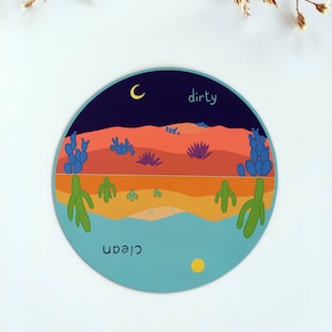 Pu&ograve; includere: Un adesivo rotondo con una scena di deserto. La met&agrave; superiore dell'adesivo &egrave; un cielo notturno blu scuro con una luna crescente. La met&agrave; inferiore rappresenta un paesaggio desertico con cactus e un lago blu. Le parole "sporco" e "pulito" sono scritte sull'adesivo.