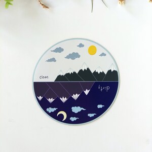 Pu&ograve; includere: Un adesivo rotondo con un design diviso. La met&agrave; superiore presenta un cielo blu con nuvole bianche e un sole giallo. La met&agrave; inferiore presenta un cielo blu scuro con nuvole bianche e una luna crescente. Il centro dell'adesivo presenta una catena montuosa con cime innevate. Il testo "clean" appare sul lato sinistro dell'adesivo e "dirty" appare sul lato destro.