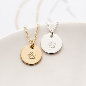Tiny discs in gold filled and sterling silver are hand stamped with a small paw print image.