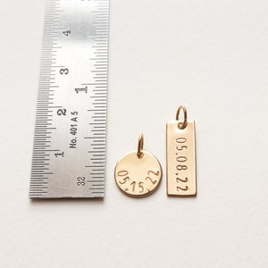 Both charms are shown next to a ruler for size reference.