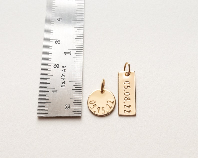 Both charms are shown next to a ruler for size reference.