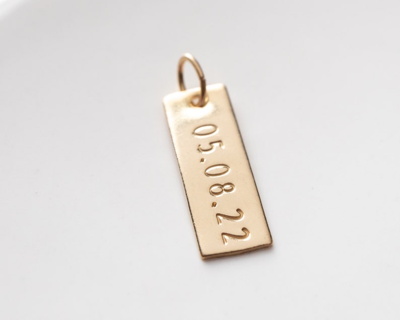 close up of the rectangle charm with the date.