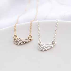 May include: Two necklaces featuring delicate wing-shaped pendants. One necklace is gold-toned with a matching gold chain, and the other is silver-toned with a matching silver chain. Both pendants have a cut-out design resembling bird feathers.