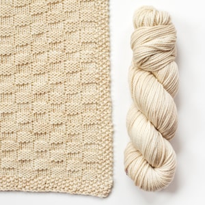 May include: A skein of beige yarn with a knitted square made from the same yarn.