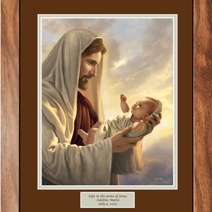 Jesús sosteniendo a un bebé, Seguro en los brazos de Jesús, cuadro personalizado enmarcado a medida.