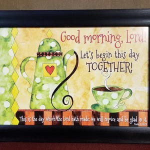 May include: A framed print with a green teapot and a cup of coffee. The text reads "Good morning, Lora! Let's begin this day TOGETHER!" and "This is the day which the Lord hath made; we will rejoice and be glad in it. Psalm 118:24".