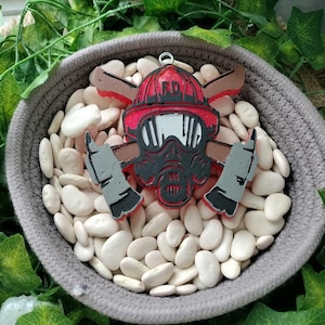May include: A red and black firefighter ornament with a gas mask, crossed axes, and the letters "FD" on the helmet.