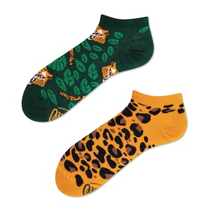 May include: A pair of ankle socks with a jungle animal print. One sock features a green background with a leopard print and leaves. The other sock features a yellow background with a leopard print.