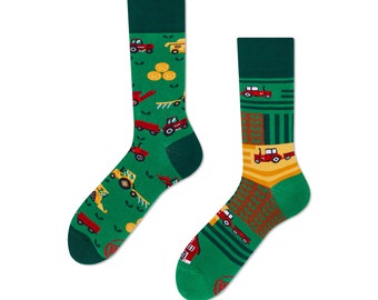 May include: A pair of green socks with a farm theme. The socks feature red tractors, hay bales, and a farmhouse.